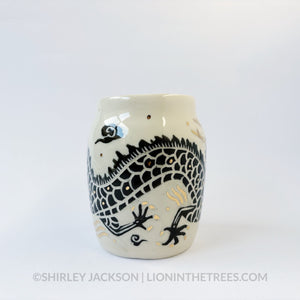 Large sgraffito vessel done with black underglaze featuring a dragon motif that curls around the entire vessel. There are also gold overglaze details throughout the piece.