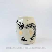 Large sgraffito vessel done with black underglaze featuring a dragon motif that curls around the entire vessel. There are also gold overglaze details throughout the piece.