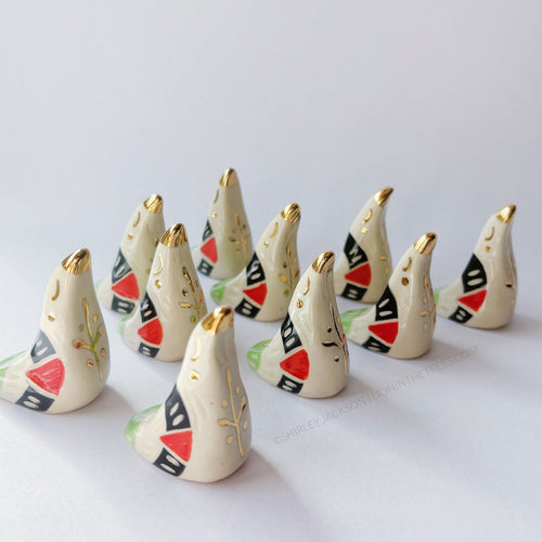 Dove totems done with black, red, and green underglazes that mimic the Palestinian flag; finished with clear glaze and gold overglaze details such as a olive tree branch motif.