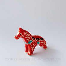 Horse totem done with red, black, and turquoise underglazes, finished with clear glaze and gold overglaze details.