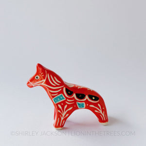 Horse totem done with red, black, and turquoise underglazes, finished with clear glaze and gold overglaze details.