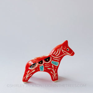 Horse totem done with red, black, and turquoise underglazes, finished with clear glaze and gold overglaze details.